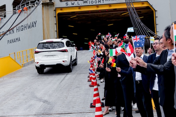 อีซูซุมิว-เอ็กซ์ขณะขนส่งขึ้นเรือเพื่อส่งออก รถอีซูซุ มิว-เอ็กซ์ ขับขึ้นเรือส่งออก โดยมีผู้ร่วมงานโบกธงนานาชาติเพื่อฉลองความสำเร็จ 3 ล้านคัน