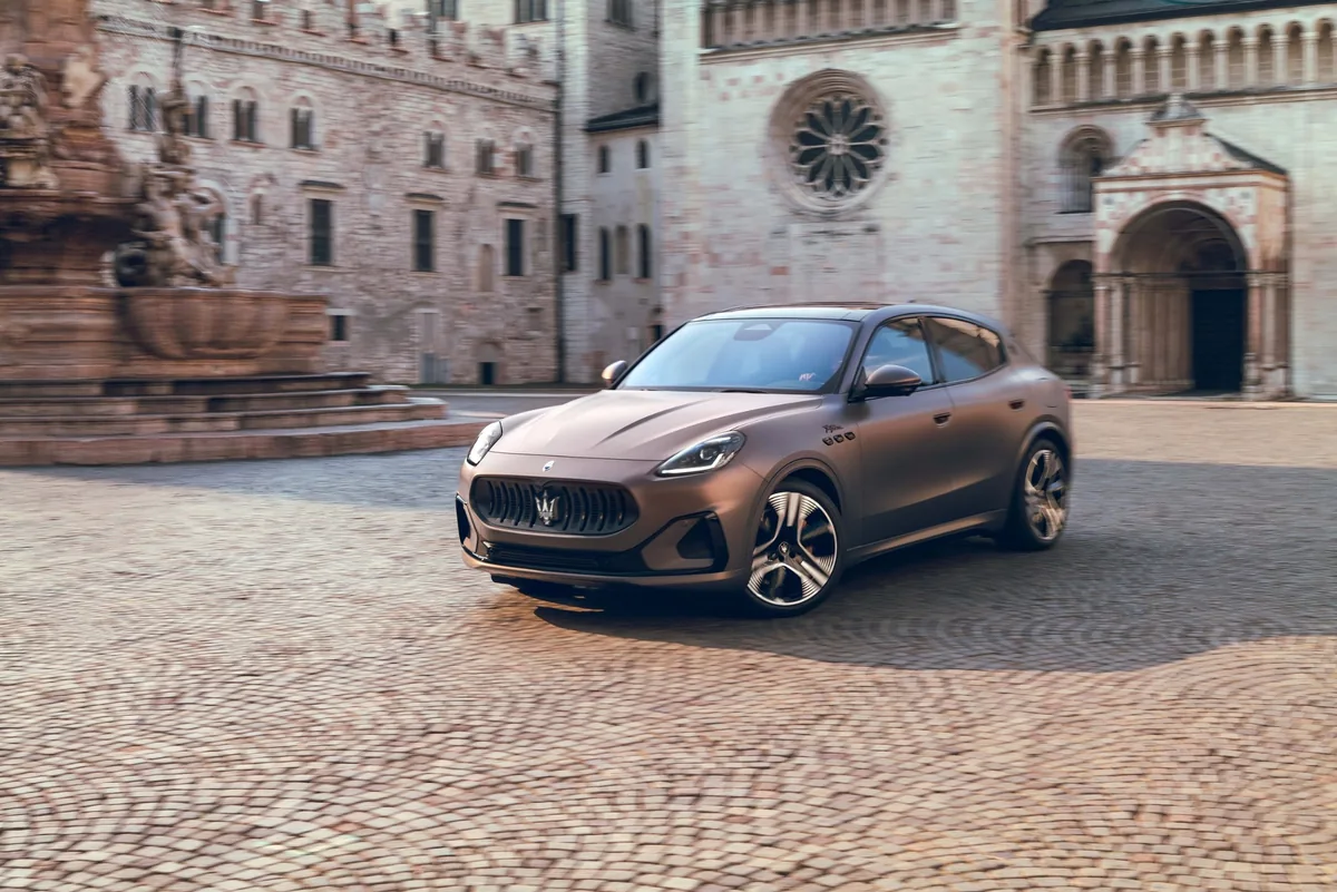 Maserati Grecale Folgore มุมหน้า 3 ส่วน Maserati Grecale Folgore รถเอสยูวีไฟฟ้าสีบรอนซ์ด้าน มุมหน้า 3 ส่วน จอดในลานเมืองเก่า