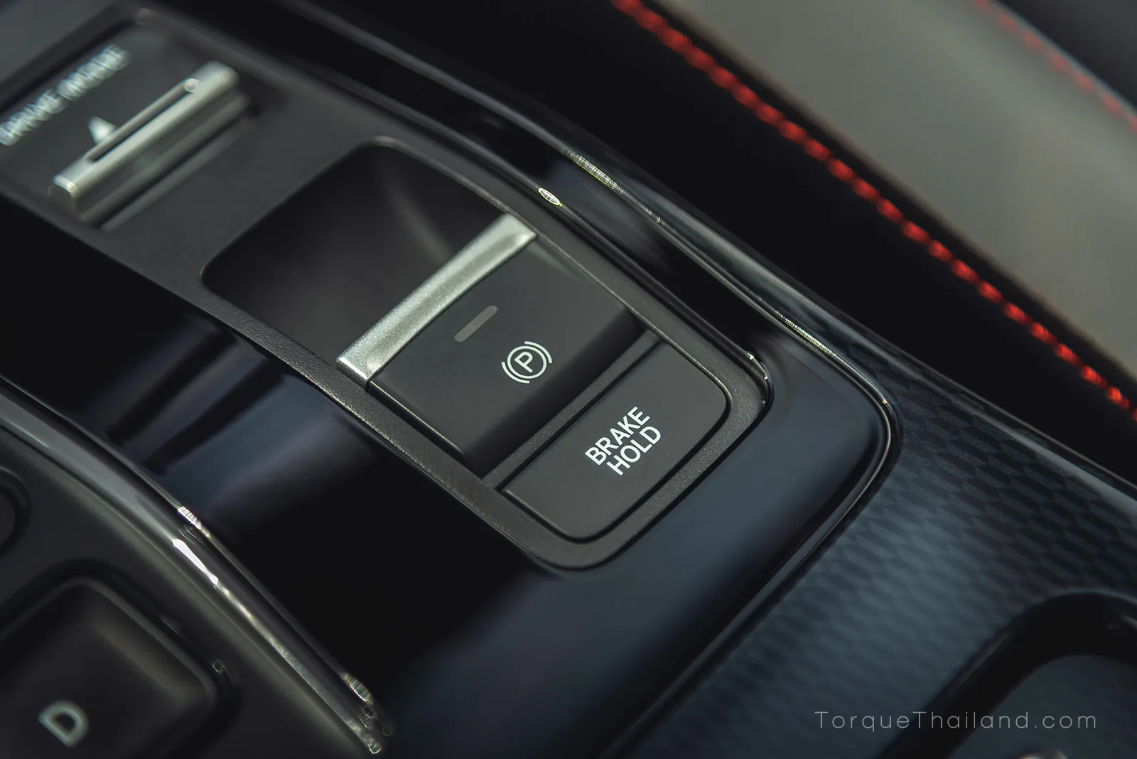 ปุ่มสั่งการระบบเบรกมือไฟฟ้า และปุ่มระบบ Auto Hold บริเวณคอนโซลกลางรถยนต์ไฟฟ้า