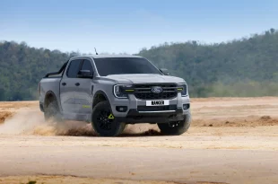 Ford Ranger Wolftrak สีเทาขณะขับบนพื้นดิน โดยมีฝุ่นฟุ้งจากล้อ มุมด้านหน้าเฉียง