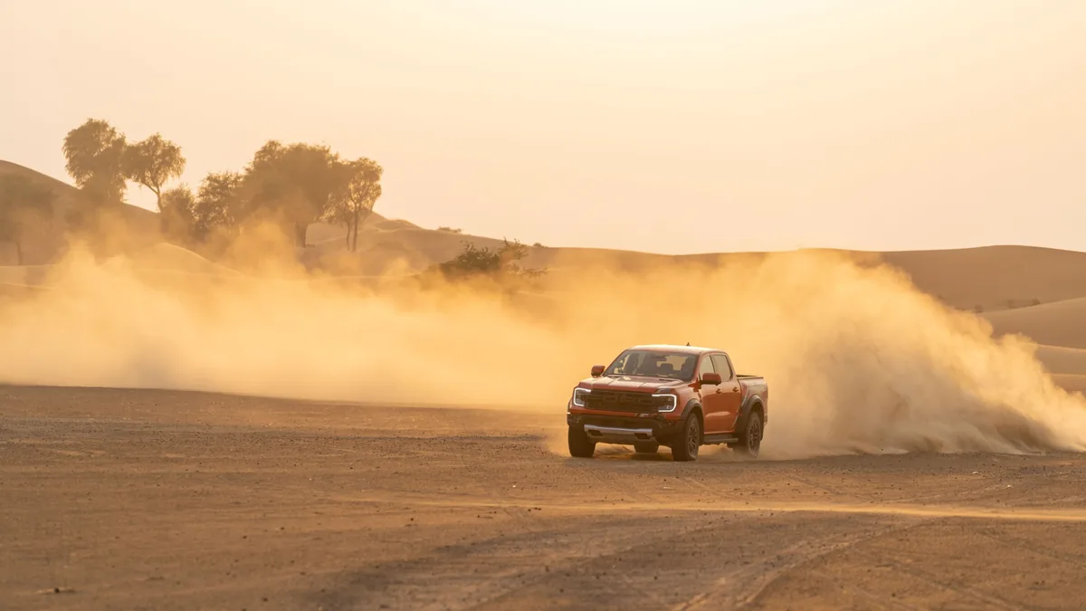 Ford Ranger Raptor กลางทะเลทราย Ford Ranger Raptor สีส้มขับบนทะเลทรายพร้อมฝุ่นฟุ้ง