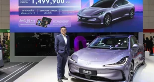 MG IM5 Exclusive Edition พร้อมบุคคลยืนข้างรถภายในบูธ และจอด้านหลังแสดงราคา 1,499,900 บาท