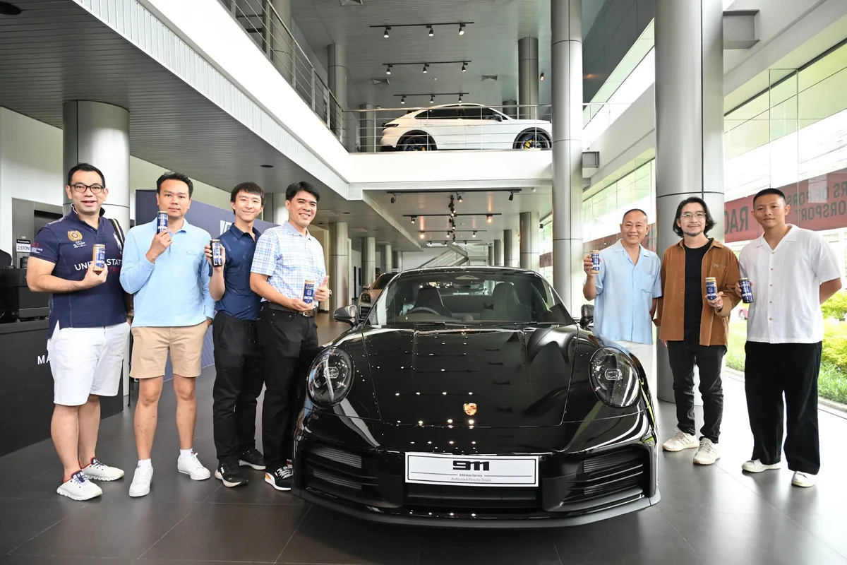 ผู้ร่วมกิจกรรมกับรถ Porsche สีดำ ผู้ร่วมกิจกรรมยืนถ่ายภาพร่วมกับรถ Porsche สีดำภายใน Porsche Centre Bangkok