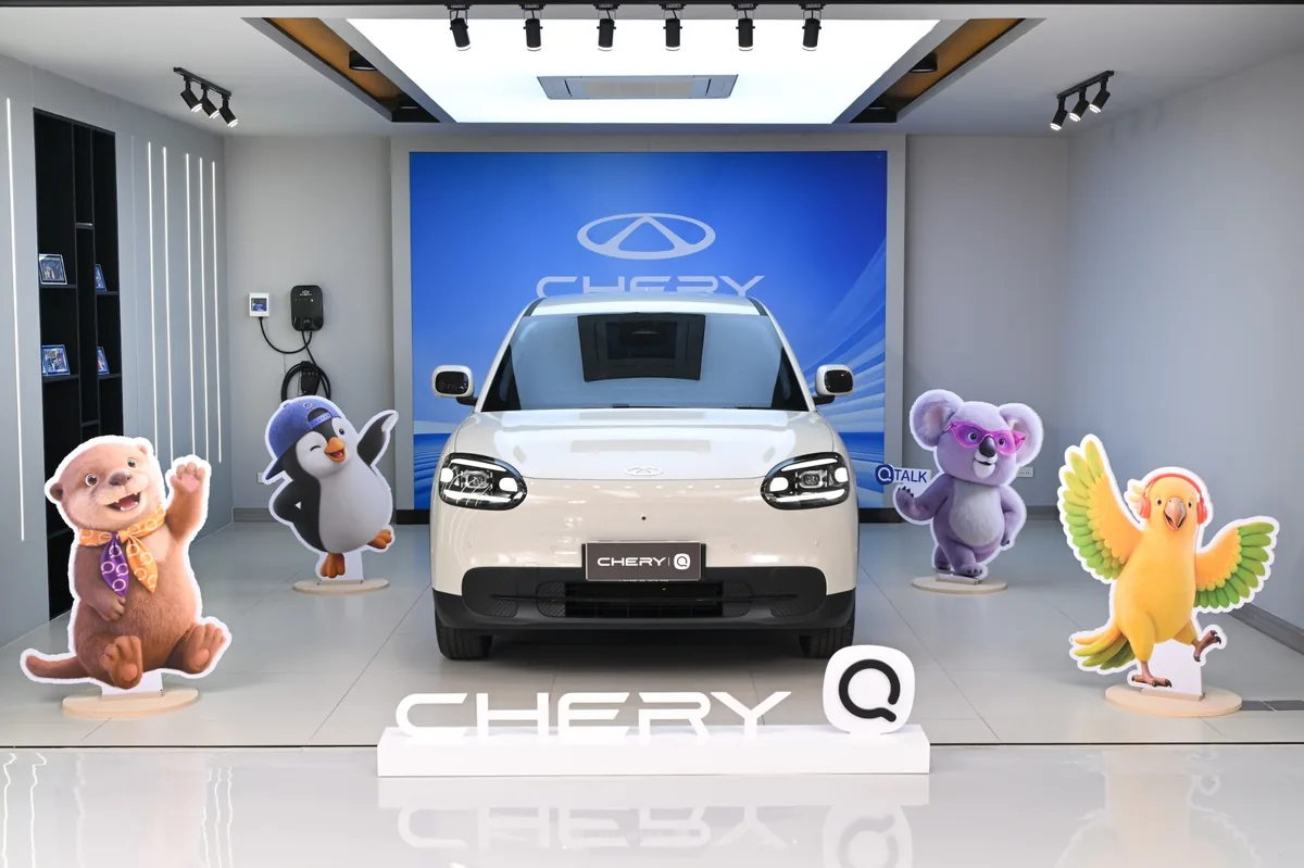 Chery Q มุมด้านหน้าจัดแสดง Chery Q สีขาวมุมด้านหน้าจัดแสดงพร้อมป้ายชื่อรุ่นและสื่อประกอบ