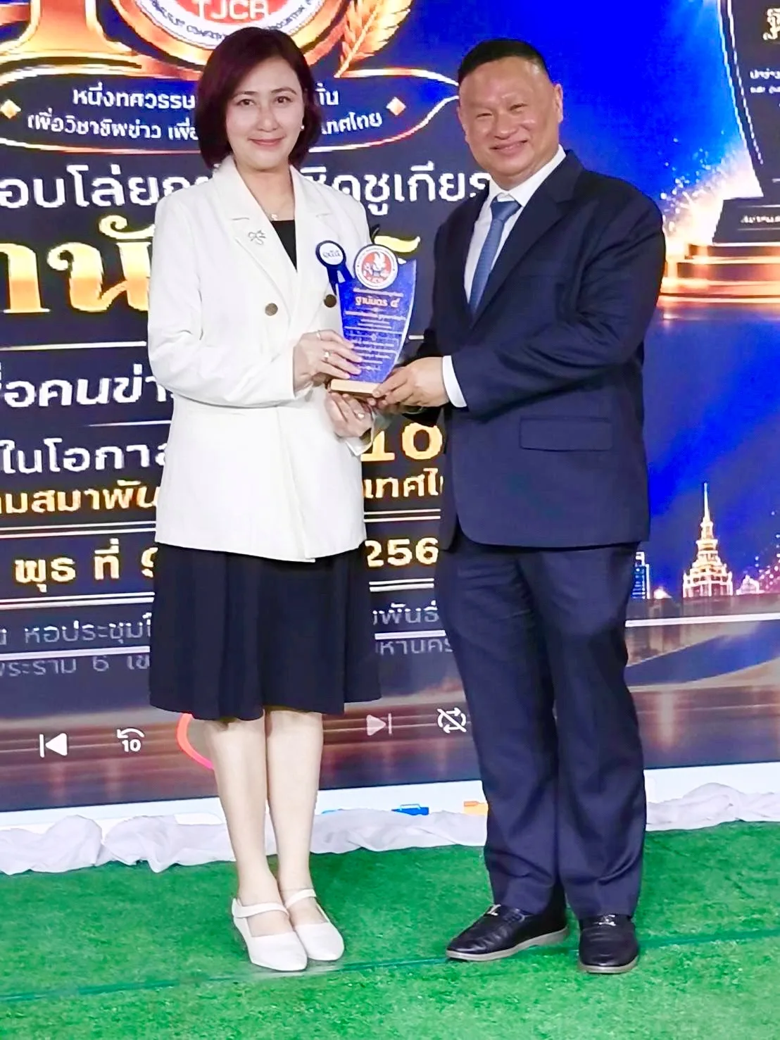 พิธีมอบรางวัลฐานันดร 4 ปี 2569 ผู้รับรางวัลฐานันดร 4 ถือโล่ร่วมกับผู้มอบรางวัลบนเวที