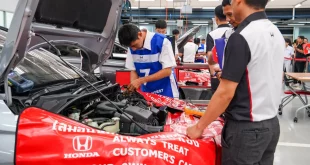 ผู้เข้าแข่งขัน Honda Skill Contest 2026 ปฏิบัติงานบริเวณห้องเครื่องรถ โดยมีผู้ดูแลกิจกรรมอยู่ใกล้เคียง