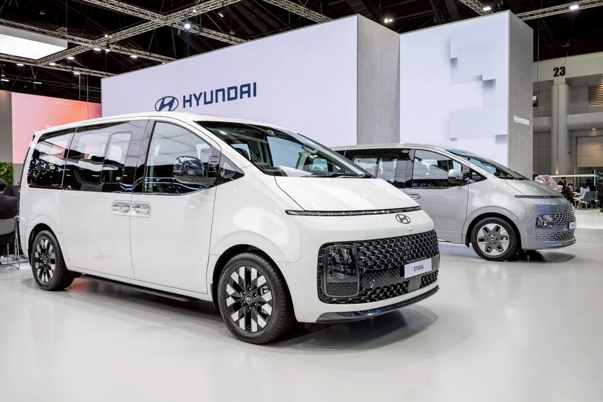 Hyundai STARIA จัดแสดง Hyundai STARIA สีขาว จัดแสดงในมุมด้านหน้าสามส่วนภายในพื้นที่แสดงรถฮุนได