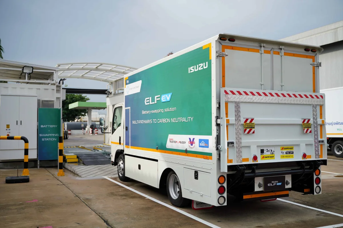 Isuzu ELF EV มุมด้านหลังข้างสถานี Battery Swapping Isuzu ELF EV มุมด้านหลังเฉียง จอดข้างสถานีสับเปลี่ยนแบตเตอรี่