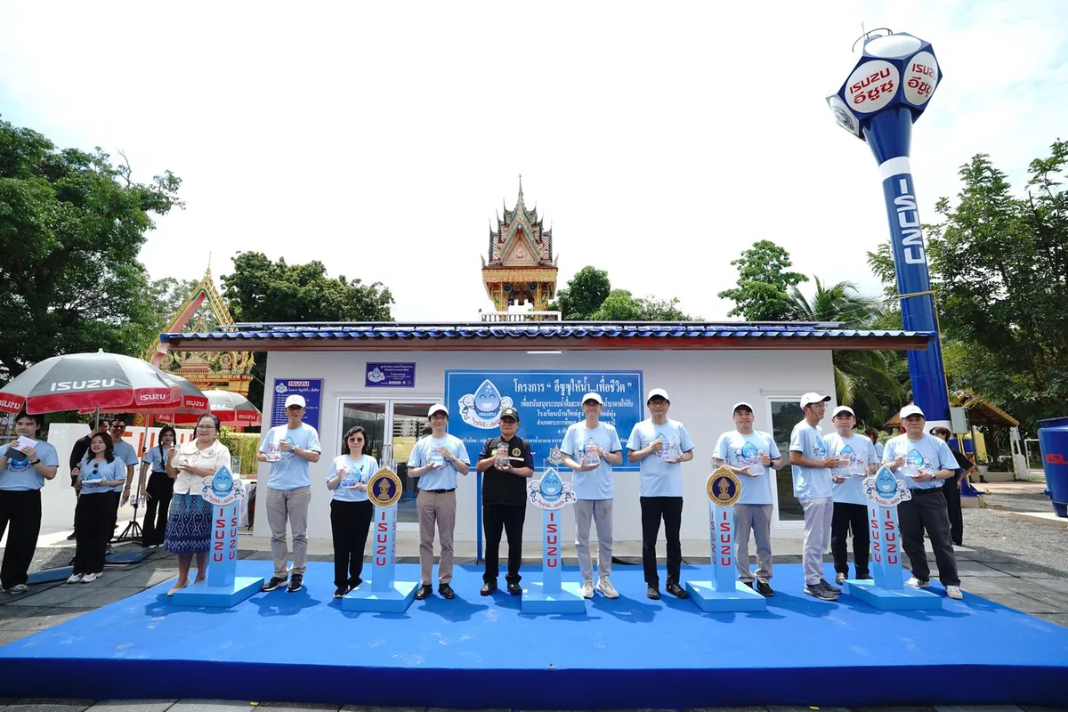ส่งมอบน้ำดื่มในโครงการอีซูซุให้น้ำ...เพื่อชีวิต คณะผู้ร่วมงานถือขวดน้ำหน้าระบบผลิตน้ำดื่มของโครงการอีซูซุให้น้ำ...เพื่อชีวิต