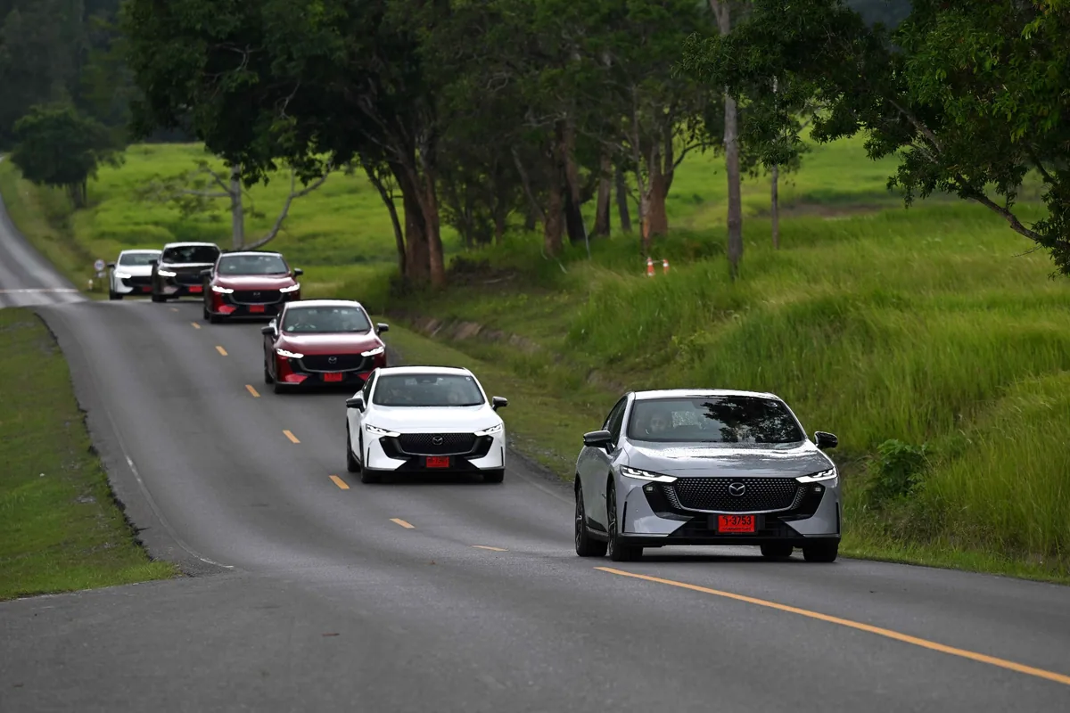 ขบวน Mazda6e ขณะขับขี่ ขบวน The All-Electric Mazda6e หลายคันขับบนถนนท่ามกลางพื้นที่สีเขียว