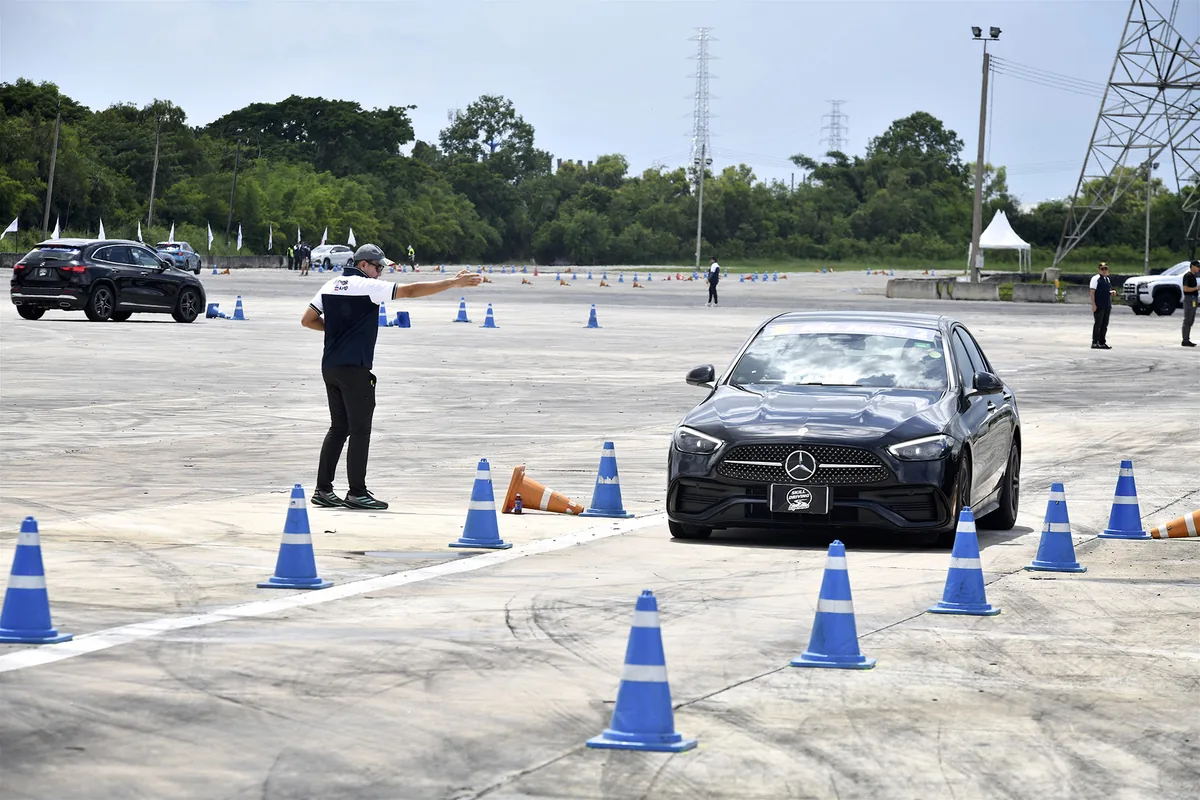 ฝึกขับผ่านกรวย Skill Driving Experience รถกำลังขับผ่านกรวยในสนามฝึก Skill Driving Experience โดยมีผู้ควบคุมกิจกรรมให้สัญญาณ