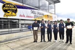 ผู้เข้าร่วมกิจกรรมยืนถ่ายภาพร่วมกันหน้าป้าย Skill Driving Experience