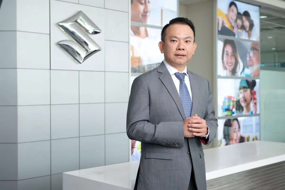 ผู้บริหารซูซูกิ มอเตอร์ ประเทศไทย ผู้บริหารของบริษัท ซูซูกิ มอเตอร์ (ประเทศไทย) จำกัด ยืนถ่ายภาพภายในสำนักงานพร้อมโลโก้ซูซูกิ