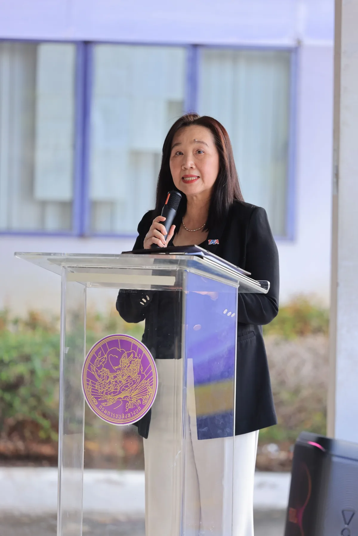 นางสาวยุพิน บุญศิริจันทร์ นายกสมาคมอุตสาหกรรมยานยนต์ไทย ผู้บรรยายยืนกล่าวเปิดงานที่โพเดียมในกิจกรรมสาธิตโครงการสถานีเบรกของ TAIA และกรมการขนส่งทางบก