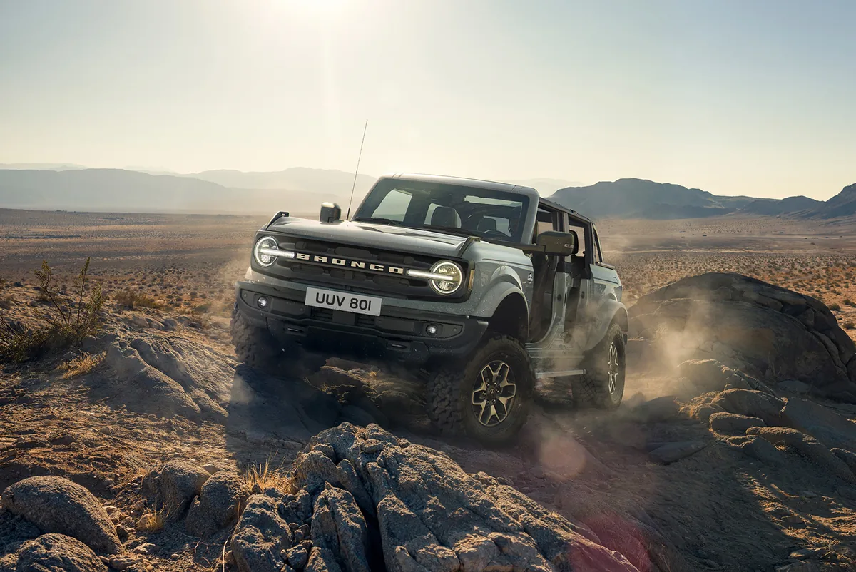 Ford Bronco ปี 2021 สีเทา มุมหน้าเฉียงขณะขับออฟโรดบนโขดหิน Ford Bronco ปี 2021 สีเทา ขณะขับออฟโรดบนโขดหิน มุมหน้าเฉียง
