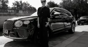มิเชล โหย่ว (Michelle Yeoh) สวมแว่นกันแดดยืนอยู่ด้านหน้ารถยนต์ SUV สีดำของ Bentley ในภาพขาวดำ