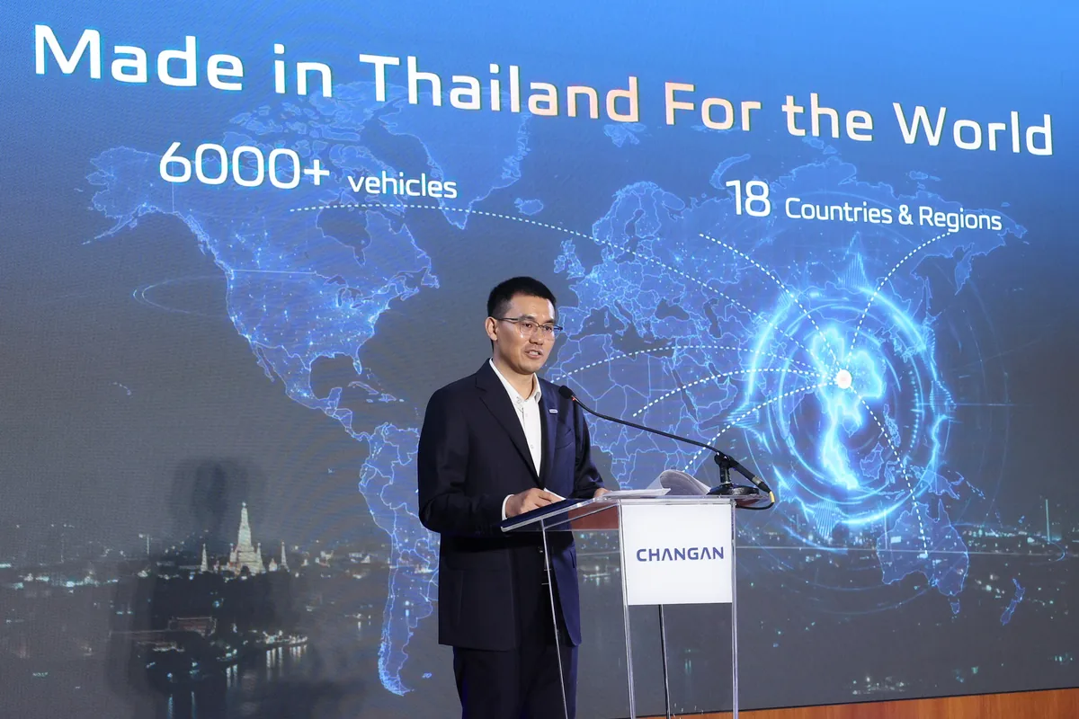 CHANGAN นำเสนอแผนผลิตในไทยส่งออกต่างประเทศ ผู้บรรยายยืนที่โพเดียม CHANGAN หน้าจอแผนที่โลกซึ่งแสดงข้อความ Made in Thailand For the World พร้อมตัวเลข 6000+ vehicles และ 18 Countries & Regions