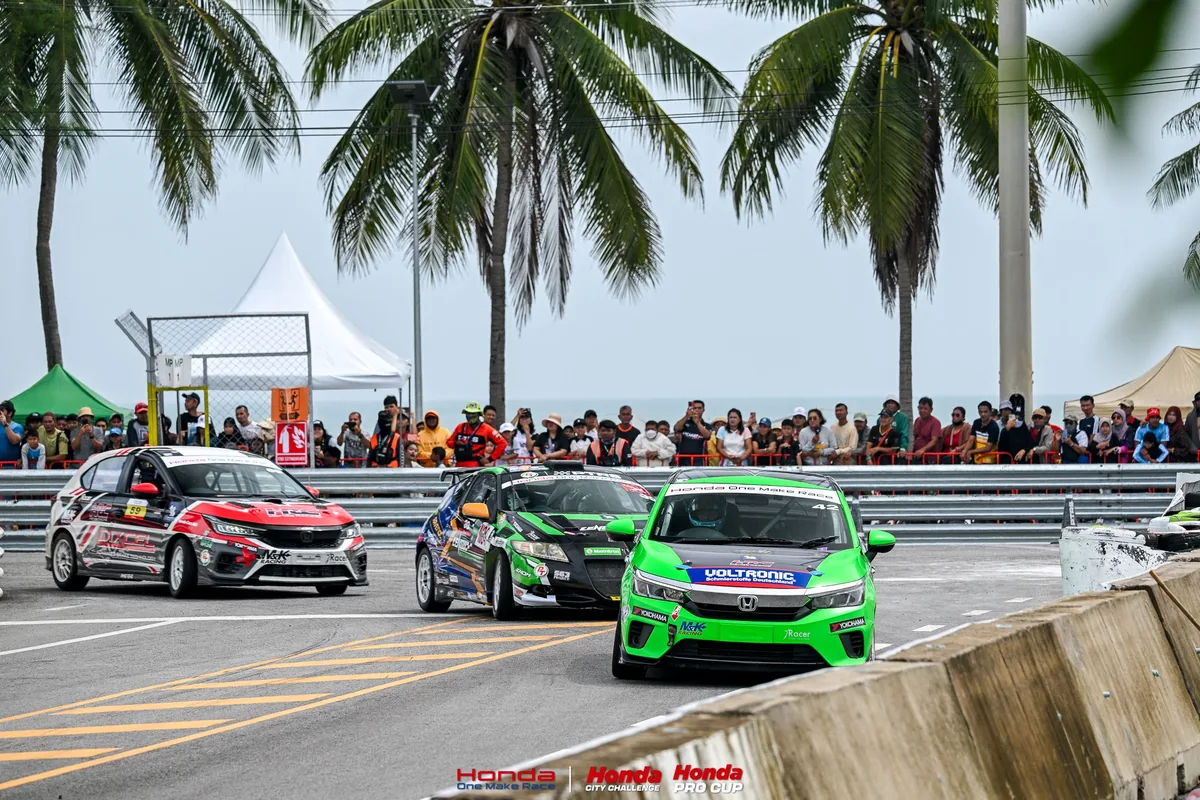 รถแข่ง Honda One Make Race ขณะเข้าโค้ง รถแข่ง Honda สามคันกำลังเข้าโค้งสนามสงขลา โดยมีผู้ชมยืนอยู่หลังแนวกั้น