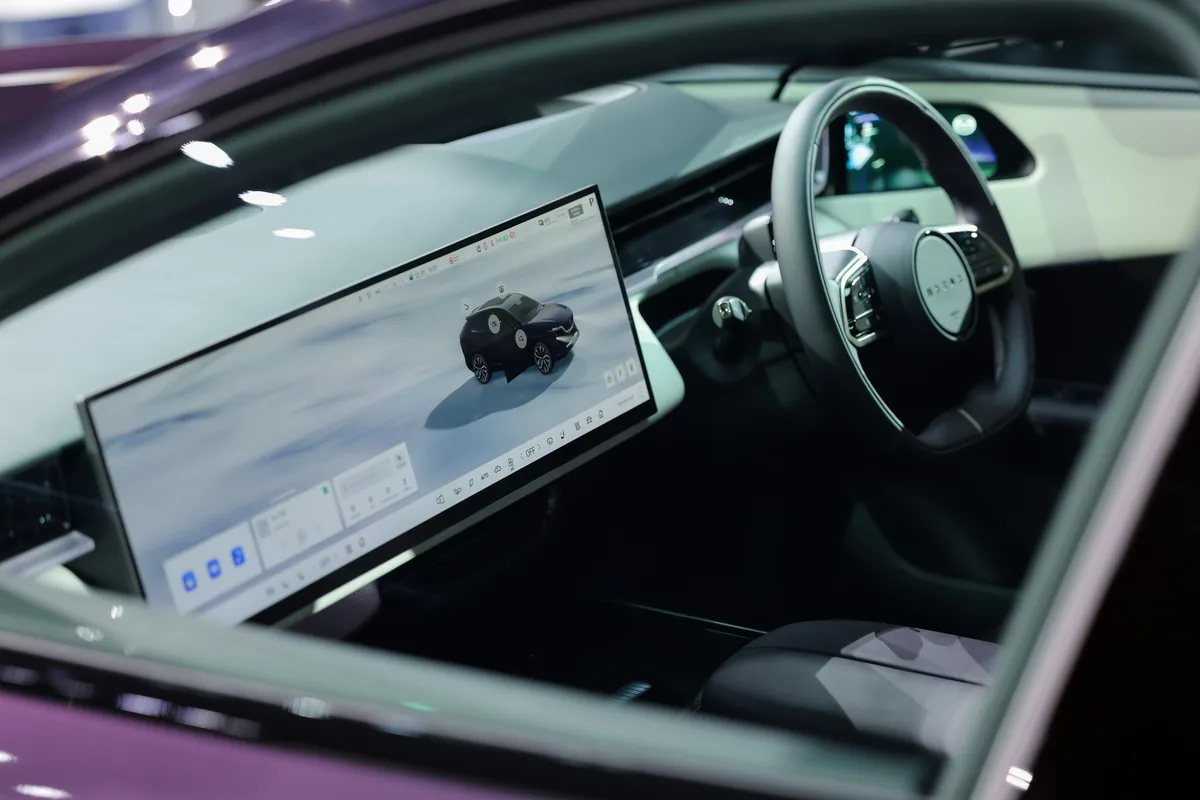 จอกลางและพวงมาลัย Mazda CX-6e จอกลางแบบแนวนอนและพวงมาลัยขวาของ Mazda CX-6e มองผ่านประตูด้านหน้า