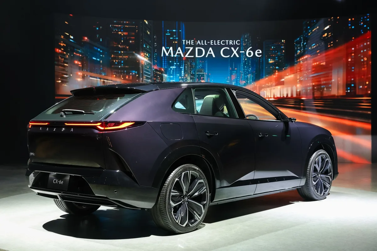 Mazda CX-6e รุ่น Premium Sports มุมท้ายสามส่วน Mazda CX-6e สีม่วงมุมท้ายสามส่วน แสดงไฟท้าย แนวหลังคาและด้านข้างตัวรถ