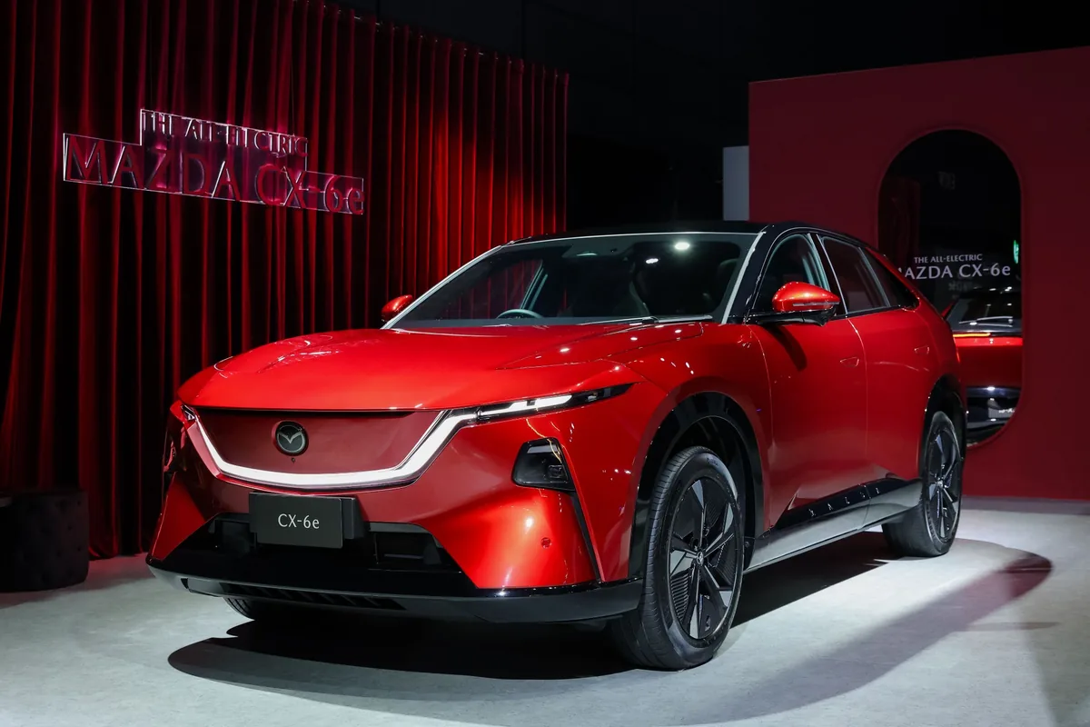 Mazda CX-6e รุ่น Premium สี Soul Red Crystal / Jet Black Mazda CX-6e สีแดงมุมหน้าสามส่วน พร้อมหลังคาสีดำในพื้นที่จัดแสดง