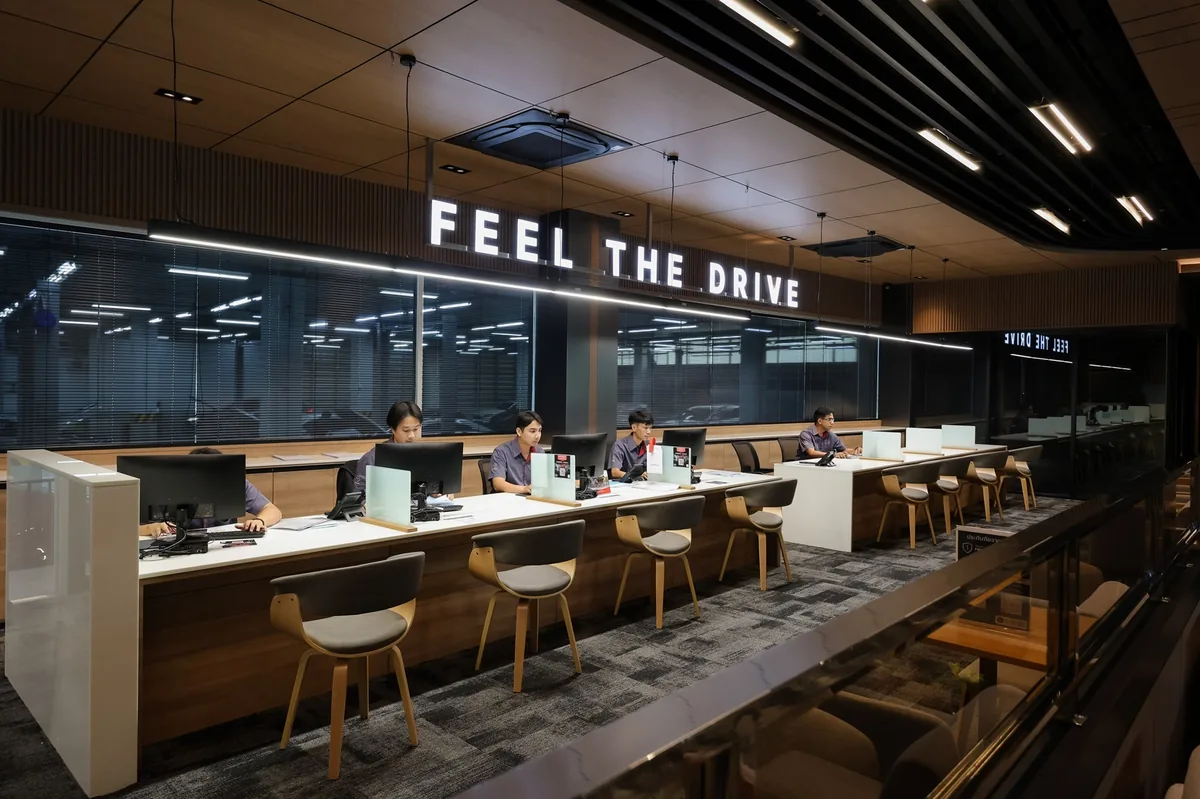 เคาน์เตอร์ต้อนรับบริการ Mazda สาทร-พระราม 3 พนักงานนั่งทำงานที่เคาน์เตอร์ต้อนรับบริการภายในมาสด้า สาทร-พระราม 3 ใต้ป้าย FEEL THE DRIVE