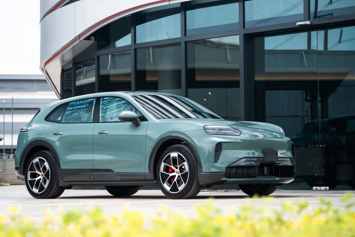 Porsche SUV สีเขียวอ่อน มุมด้านหน้าเฉียง Porsche SUV สีเขียวอ่อน มุมด้านหน้าเฉียง จอดอยู่หน้าอาคารกระจก