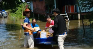 ผู้ร่วมกิจกรรมช่วยกันขนย้ายกล่องสิ่งของลงเรือในบริเวณชุมชนที่มีน้ำท่วมขัง
