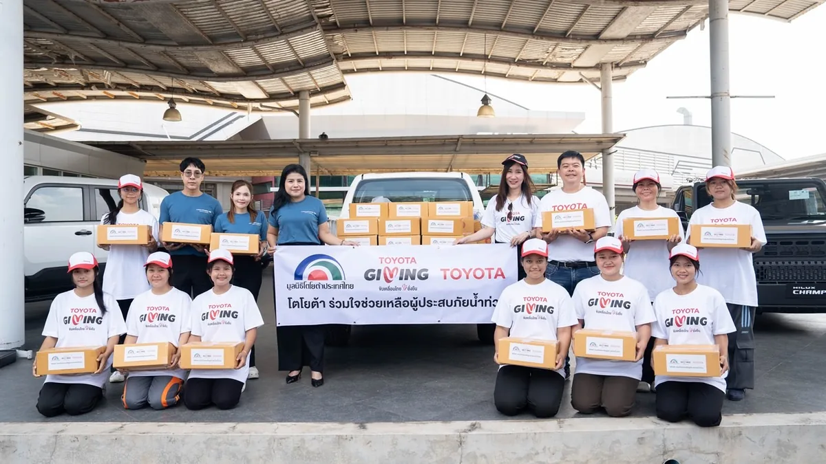 กลุ่มผู้ร่วมกิจกรรมโตโยต้าพร้อมกล่องช่วยเหลือน้ำท่วม กลุ่มผู้ร่วมกิจกรรม TOYOTA GIVING ถือกล่องช่วยเหลือผู้ประสบภัยน้ำท่วม พร้อมรถกระบะและป้ายโครงการ
