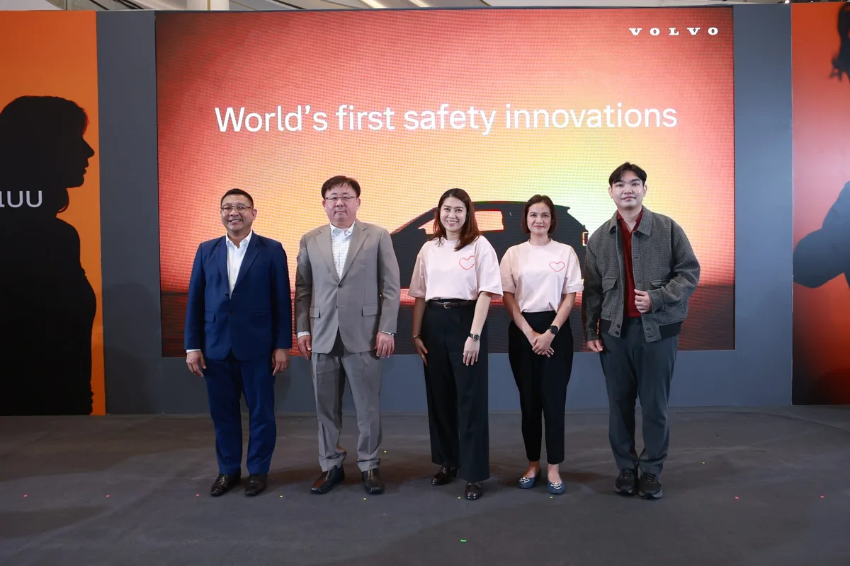 ผู้ร่วมงาน Volvo Excellence หน้าเวทีนิทรรศการ ผู้ร่วมงาน Volvo Excellence 2026 จำนวนห้าคนยืนถ่ายภาพหน้าเวทีที่มีข้อความ World's first safety innovations